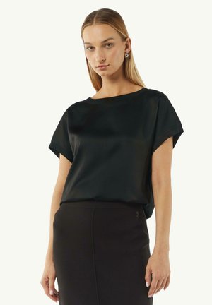 Black short-sleeve top made of a smooth, lightweight fabric with a slightly loose fit and a wide neckline, paired with a fitted black skirt.