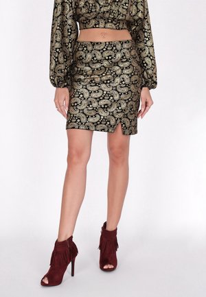 Schwarzer und goldener Paisleymuster-Minirock mit einem seitlichen Schlitz, kombiniert mit bordeauxfarbenen Fransen-Stiefeletten aus Wildleder.