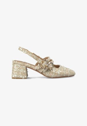 Beaded beige slingback shoe with a square toe and block heel. Features dual front straps adorned with metallic accents. Textured fabric.