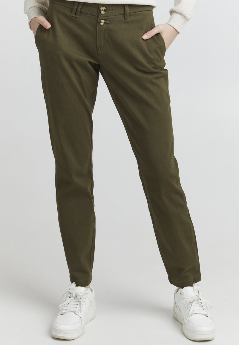 Olive green pants in a slim fit, made of soft cotton material. Features two front pockets and a double-button closure. Paired with white sneakers.