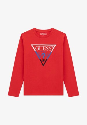 Puna pika pikkade varrukatega särk, mis on valmistatud orgaanilisest puuvillast, sisaldab kolmnurkset graafikat, kus on sinise ja musta värviga kirjas "GUESS®", "U.S.A." ning küsimärgid.