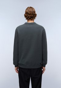 Sudadera verde oscura con cuello redondo, puños y dobladillo acanalados. Textura suave, diseño sencillo y corte relajado, mostrada desde la parte posterior.