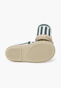 Stribet slip-on sko med grøn og hvid vævet stof, en struktureret beige sål og en fletdetalje omkring bunden.