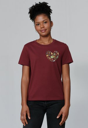 T-shirt en coton bordeaux avec un col rond et des manches courtes, présentant un design de cœur coloré sur la poitrine gauche.