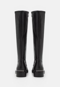 Bottes noires en cuir montantes avec une finition lisse, fermeture éclair et semelle robuste. Dotées de coutures verticales pour un détail supplémentaire.