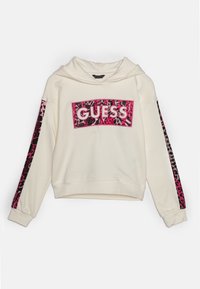 Cream hoodie med ett panel i rosa leopardmönster som har "GUESS"-loggan centrerad. Långa ärmar med matchande mönster på sidorna. Strukturerad tyg.