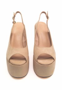 Sandali platform in suede beige con punta aperta e design slingback. Presentano una soletta rotonda e una cinghia alla caviglia regolabile con accessori in oro.
