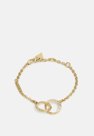 Bracelet chaîne en or avec deux anneaux entrelacés, l'un gravé avec du texte et l'autre serti de petites pierres claires.