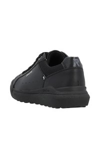 Chaussure de sport noire en matériaux mesh et cuir, de forme arrondie, avec une semelle texturée et un logo distinctif sur le panneau arrière.