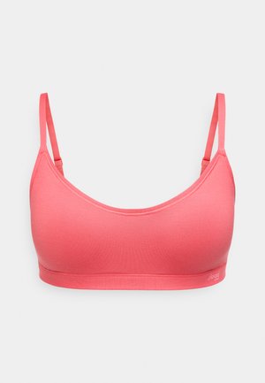 Naadloze zacht koraalroze stoffen bralette met verstelbare dunne bandjes en elastische onderband, voorzien van een subtiel logo aan de rechteronderkant.
