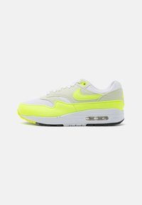 Sneaker alb și galben neon, confecționat din materiale de suede și plasă, având o pernuță de aer vizibilă, design cu șireturi și talpă neagră.