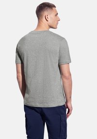 Šedé bavlněné tričko s kulatým výstřihem, krátkými rukávy a volným střihem, nosené s námořnickými cargo šortkami, ukazující jednoduchou, hladkou texturu.