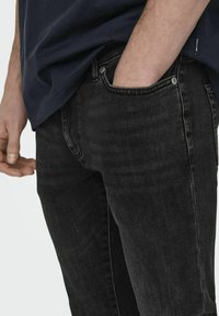 Sorte denim jeans med slim fit, med subtil fading, standard lommer og metal knapdetaljer på taljen.