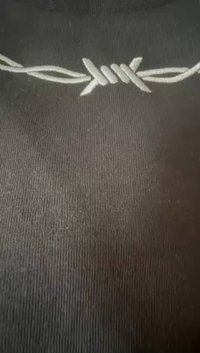 Crni tekstil s rebrastom teksturom s bijelim vezenim žicom duž gornjeg dijela.