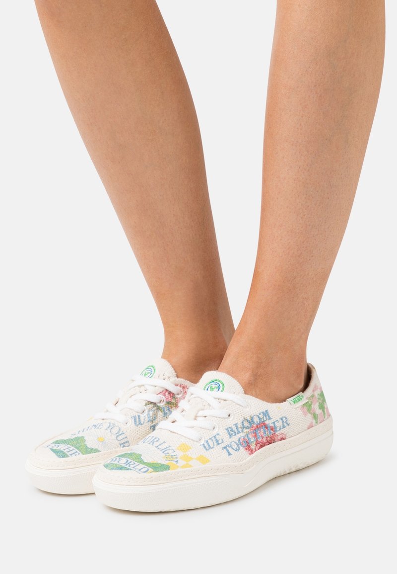 Baskets en toile avec motifs floraux et graphiques multicolores, lacets blancs, accents verts et semelle texturée.