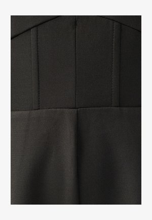 Melna kleita ar strukturētu dizainu, vertikālām šuvēm un smalkām tekstūrām, izgatavota no gluda, viegla auduma.