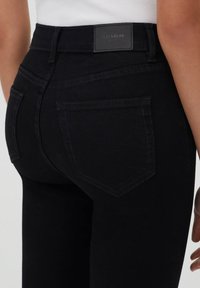 Černé džíny z denimu s vysokým pasem, s dvěma zadními kapsami a nášivkou s logem Pull&Bear. Hladká textura a přiléhavý střih.