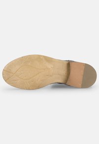 Suela de zapato con superficie de goma texturizada y un tacón de color marrón claro. Presenta patrones intrincados y un acento de corcho en la base.