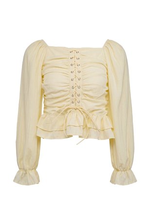 Blouse jaune clair à manches longues avec manches bouffantes, devant froncé, détail lacé et ourlet volanté aux poignets et à la taille.