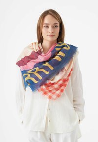 Grote sjaal met patroon, gekenmerkt door een mix van roze, blauw en oranje tinten, met een geruit ontwerp en vetgele letters, gemaakt van een zachte, lichte stof.