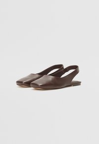 Brūni ādas slingback apavi ar kvadrātu purngalu, plakanu zoli un minimālistisku dizainu, kas izceļas ar mīkstu tekstūru un bez redzamām rotām.