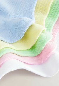 Chaussettes en coton colorées superposées en vagues : bleu clair, jaune, vert, rose et blanc. Texture douce avec un design côtelé et des bords arrondis.