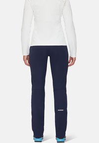 Marinefarbene Wanderhosen mit schlankem Schnitt, aus dehnbarem Material. Mit einem Logo am unteren rechten Bein und einer Reißverschlusstasche.