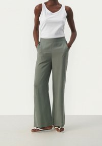 Relaxed-fit, wide-leg pants in a soft, olive-green fabric with a smooth texture, featuring side pockets and a high waistband.