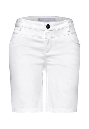 Zbliżenie na tylną kieszeń białych spodni z metalowym nitonikiem i małą czarną etykietą marki, noszone z niebiesko-białą pasiastą koszulą.