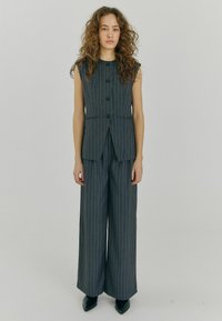 Hall grey pinstripe vest ja laia jala püksid, millel on ilma varrukateta disain, viis nuppu ja kohandatud sobivus. Materjal näeb välja sile ja struktureeritud.