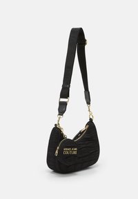 Svart quiltad handväska med rundad form, guldfärgade detaljer, framficka med blixtlås och en justerbar rem med präglad text.