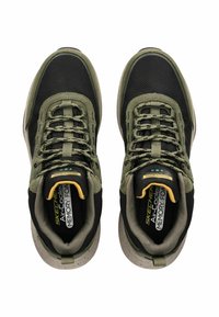 Tmavě zelené a černé sportovní boty s prodyšným svrškem, texturovanými detaily a tečkovanou gumovou podrážkou. Obsahují šněrování a polstrovaný límec.
