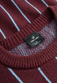 Wino-czerwony sweter z dzianiny w jasnoniebieskie poziome paski i prążkowanym kołnierzem. Posiada czarną metkę z białym napisem "Johnny Urban", rozmiar M.