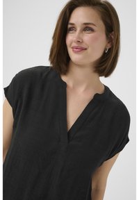 Blouse noire texturée avec un décolleté en V et des manches courtes. Possède une coupe décontractée et un motif subtil, fabriquée en tissu léger.