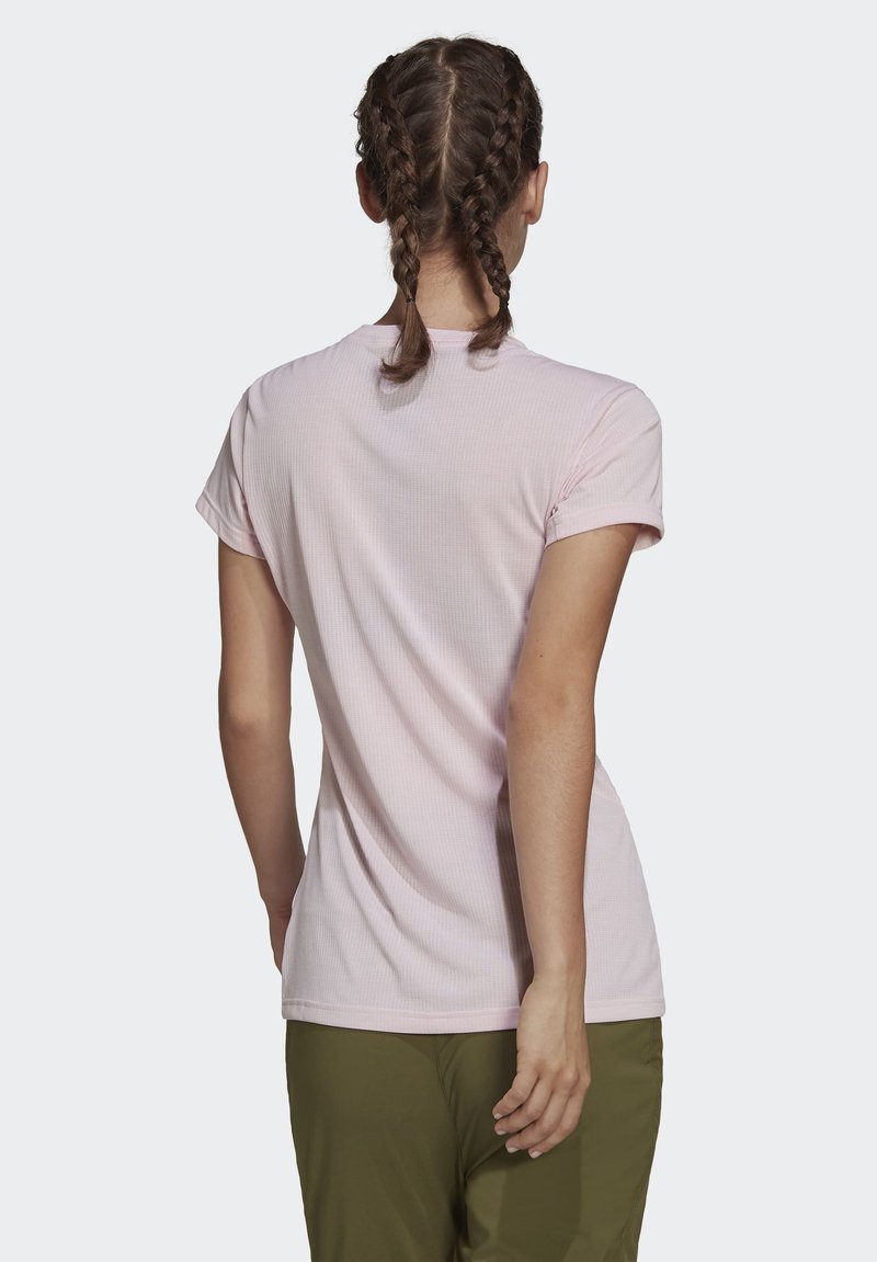 Helles rosa Kurzarm-T-Shirt aus strukturiertem Stoff; mit einem runden Ausschnitt und lockerer Passform, kombiniert mit olivgrünen Hosen.