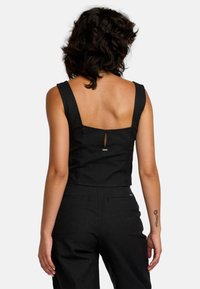 Zwart crop top met een vierkante halslijn en brede bandjes. Heeft een sleutelgat uitsparing aan de achterkant en een metalen accent nabij het midden.