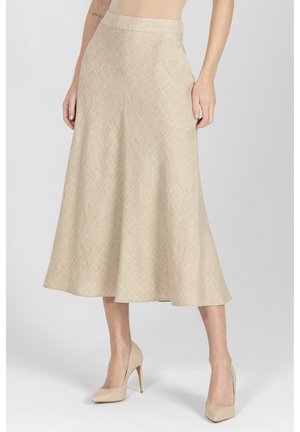 Beżowa spódnica midi w kształcie litery A z subtelnym teksturowanym wzorem, noszona z cielistymi szpilkami na jasnym tle.