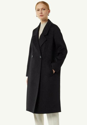 Cappotto di lana nera con design doppiopetto, rever oversize, tasche laterali e una texture liscia.