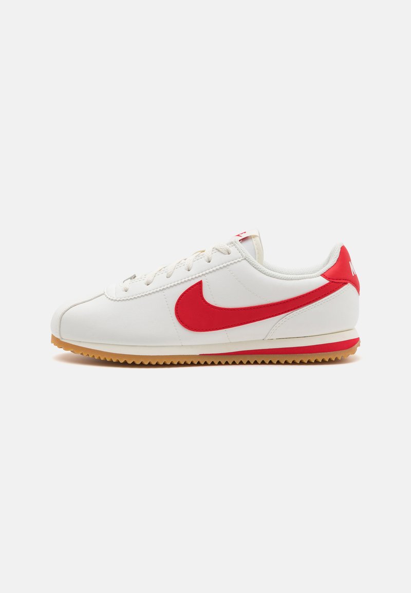 Nike Low-Top-Sneaker mit einem weißen Lederobermaterial, roten Akzenten und einer Gummisohle. Schnürdesign mit strukturierten Seitenpaneelen.