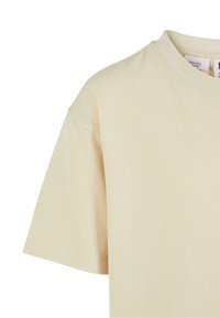 Bēšas krāsas T-krekls ar īsām piedurknēm un apaļu kakla izgriezumu, redzama kakla un plecu šuve, vienkāršs dizains, iekšpusē apkakles auduma etiķete.