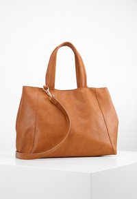 Tan leather tote bag with dual handles and an adjustable shoulder strap. Smooth texture, minimalist design, and no visible hardware accents.