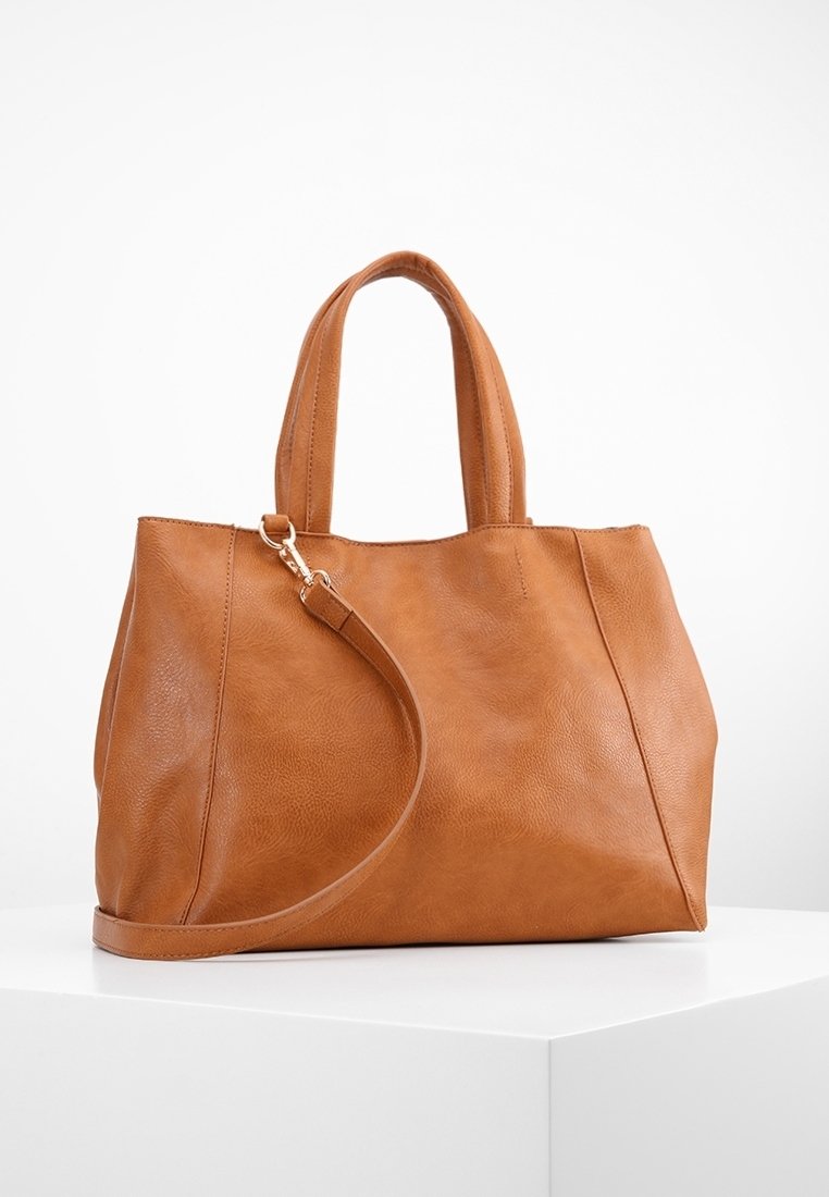 Tan leather tote bag with dual handles and an adjustable shoulder strap. Smooth texture, minimalist design, and no visible hardware accents.