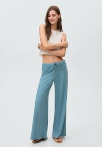 Wide-leg, light blue pants made of soft fabric with a drawstring waist. Features a smooth texture and relaxed fit, suitable for casual wear.