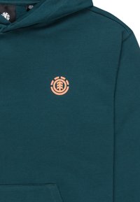 Teal huppari, jossa on iso etutasku, säädettävä nyöri huppu ja oranssi pyöreä logo rinnassa. Pehmeä puuvillasekoitekangas.