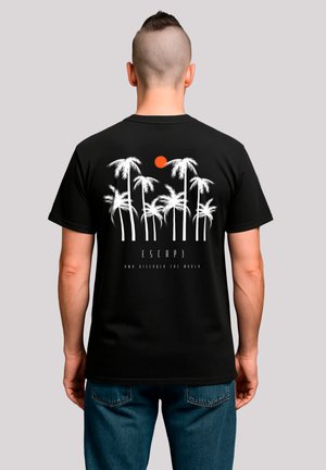 Schwarzes Baumwoll-T-Shirt mit weißen Palmen-Grafiken und einer orangefarbenen Sonne. Der Text lautet "ENTFLIEHEN UND DIE WELT ENTDECKEN" unter dem Design.