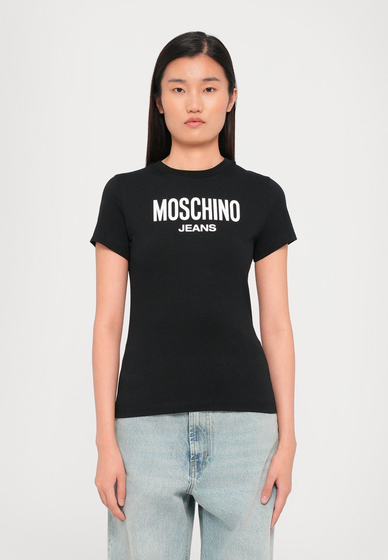 Juoda medvilninė marškinėliai su trumpomis rankovėmis, su baltu "MOSCHINO JEANS" logotipu, esančiu centre ant krūtinės. Prigludęs dizainas ir apvalus iškirpimas.