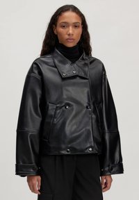 Schwarze Lederjacke mit einem zweireihigen Design, oversized Fit, breitem Kragen und Druckknopfdetails an den Ärmeln und Fronttaschen.