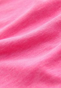 Mekana ružičasta tkanina s finom pletenom teksturom i nježnim naborima koji stvaraju suptilne sjene i naglaske.