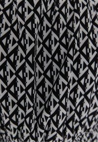 Tissu à motif géométrique noir et blanc avec des triangles et des rectangles imbriqués créant un design abstrait répétitif.