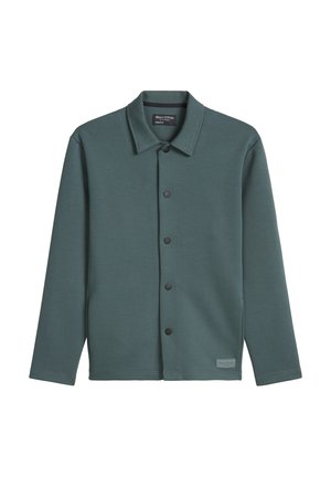 Donkergroen jack met lange mouwen en knopen, voorzien van een kraag, matte zwarte drukknopen en een klein stoffen merklipje bij de zoom.